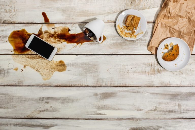 Cup of coffee spilled on wooden floor.